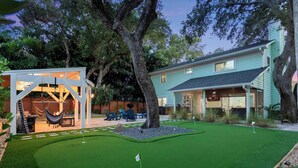 A residential property with a well-maintained lawn, a small gazebo, and a house with a porch.