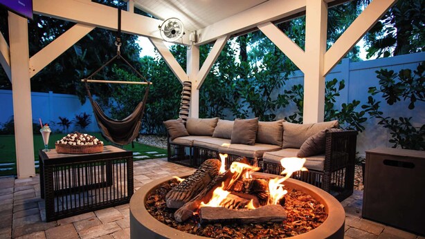 An outdoor seating area with a fire pit, cushioned seating, and a hanging chair.