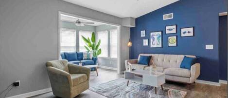 Un salon doté d’un ventilateur de plafond, de deux canapés, d’une table basse et d’un tapis à motifs.