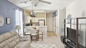 Un salon comprenant un canapé, un téléviseur et un coin repas avec des chaises et une table.