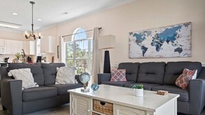 Un salon avec deux canapés gris, une table basse blanche et une carte du monde accrochée au mur.