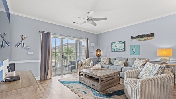 A living room with a ceiling fan, a sofa set, a coffee table, and a view through a glass door to the outside. - Captains Quarters In Myrtlewood Villas (Myrtle Beach)
