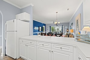 A kitchen with white cabinetry, a built-in island, and a ceiling fan. - Captains Quarters | Private Balcony + Resort Pool (Myrtle Beach)
