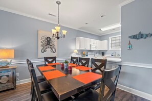 A dining area with a wooden table, chairs, and orange placemats.