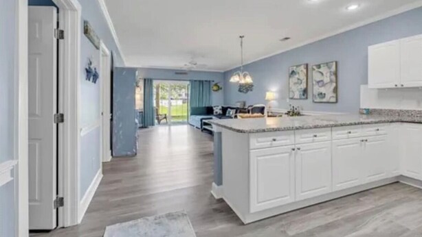 A modern kitchen with white cabinets, a large island, and pendant lighting.