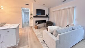 Una sala de estar moderna con un sofá, un televisor montado en la pared y una chimenea.