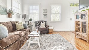 Een woonkamer met een bruine leren bank, een witte salontafel, een zwarte leren fauteuil en een houten kast.