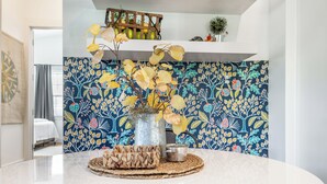 Een keuken met een decoratieve spatwand, een houten plank en een tafel met een geweven placemat.