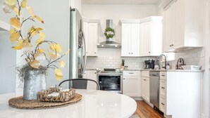 Een moderne keuken met witte kasten, roestvrijstalen apparatuur en een ronde eettafel met decoratief middelpunt.