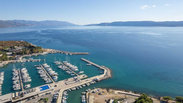 Vista aérea de un puerto deportivo con barcos amarrados, un muelle y un edificio con techo azul.