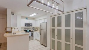A modern kitchen with white cabinets, a central island, and a built-in microwave.