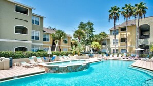 A swimming pool with lounge chairs and palm trees.