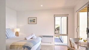 A bedroom with a bed, a bedside lamp, a picture on the wall, and a view of the outside balcony. - Bicheno Ocean Views Apt 2 - Bicheno Accommodation (Bicheno)