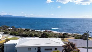 A coastal residential area with houses, a clear blue sky, and the ocean. - Bicheno Ocean Views Apt 2 - Bicheno Accommodation (Bicheno)