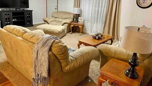 Una sala de estar con sofá, sillón, mesa de centro y mueble para televisión.