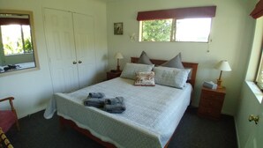 A bedroom with a bed, two bedside tables, a chair, a wardrobe, and a window. - Cherry Tree Lane Accommodation, Quiet location bordered by farmland. (Te Awamutu)