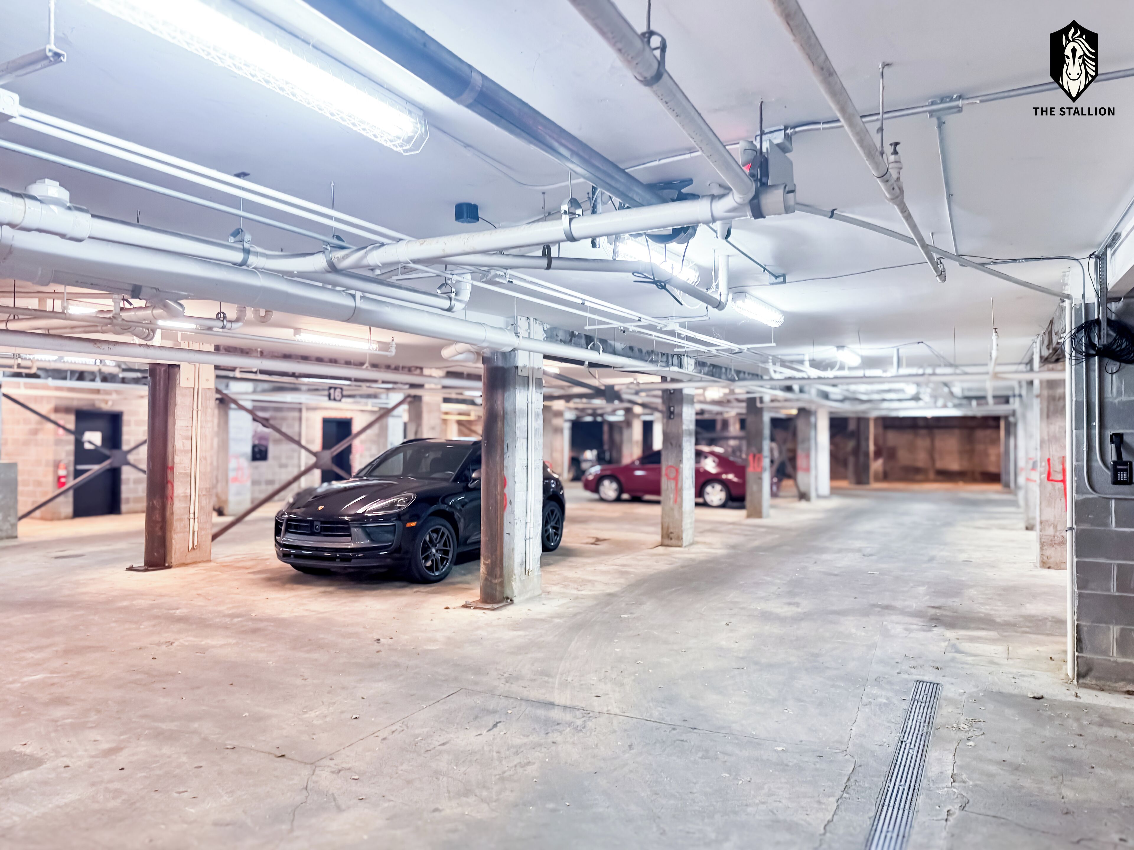 A parking garage with multiple levels, concrete floors, and exposed pipes.