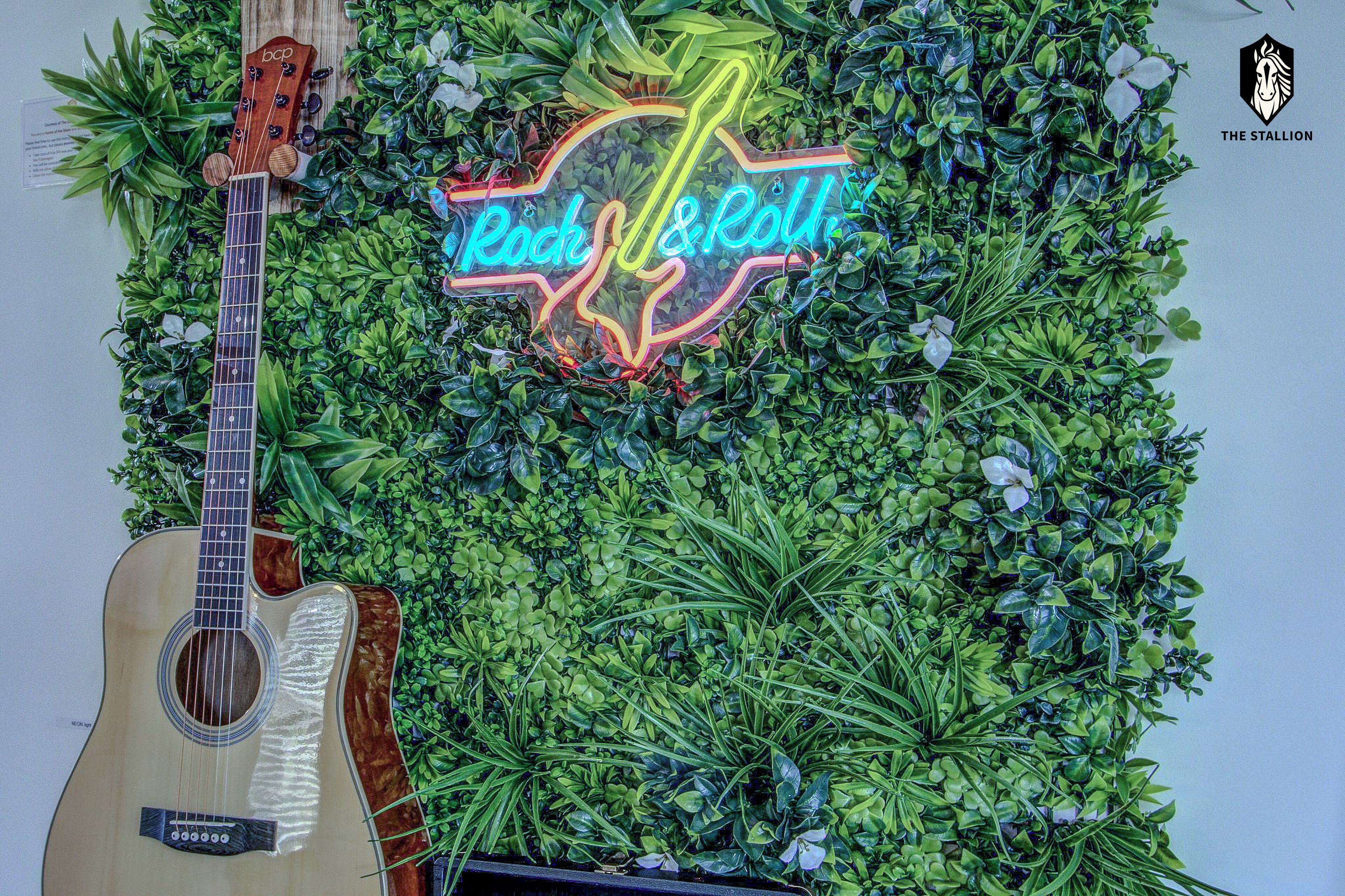 A guitar leaning against a wall with a neon sign that reads 'Rock & Roll'.