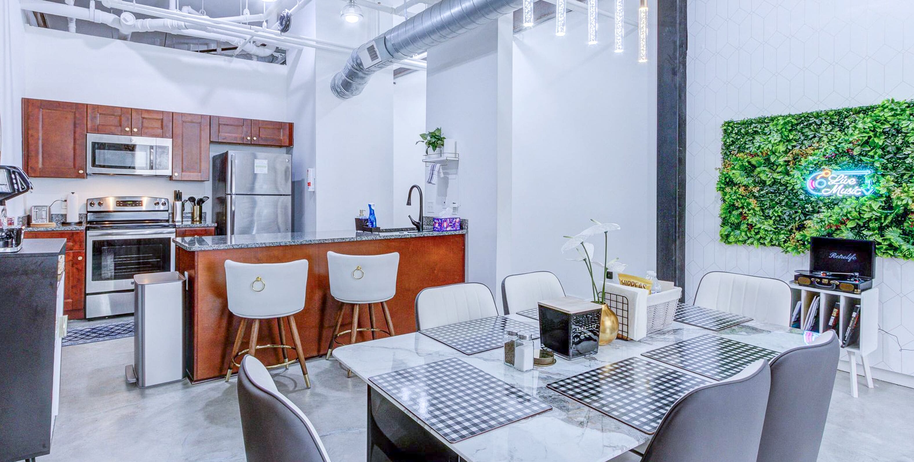 A modern kitchen with stainless steel appliances, a bar area, and a dining space with a checkered tablecloth.