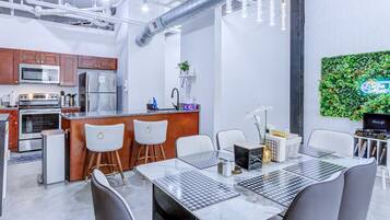 A modern kitchen with stainless steel appliances, a bar area, and a dining space with a checkered tablecloth.