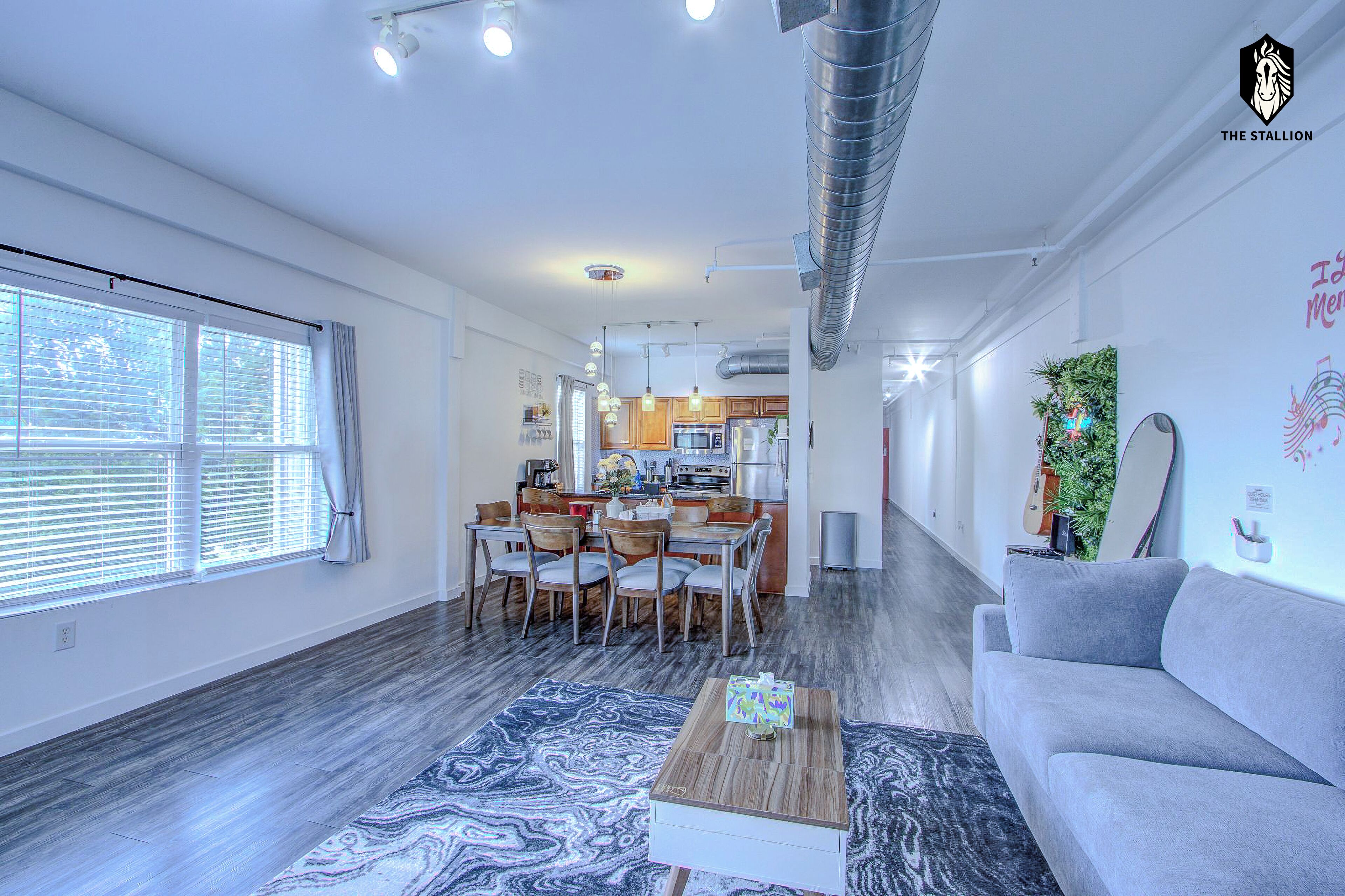 A modern living space with a dining area, kitchen, and a sofa.