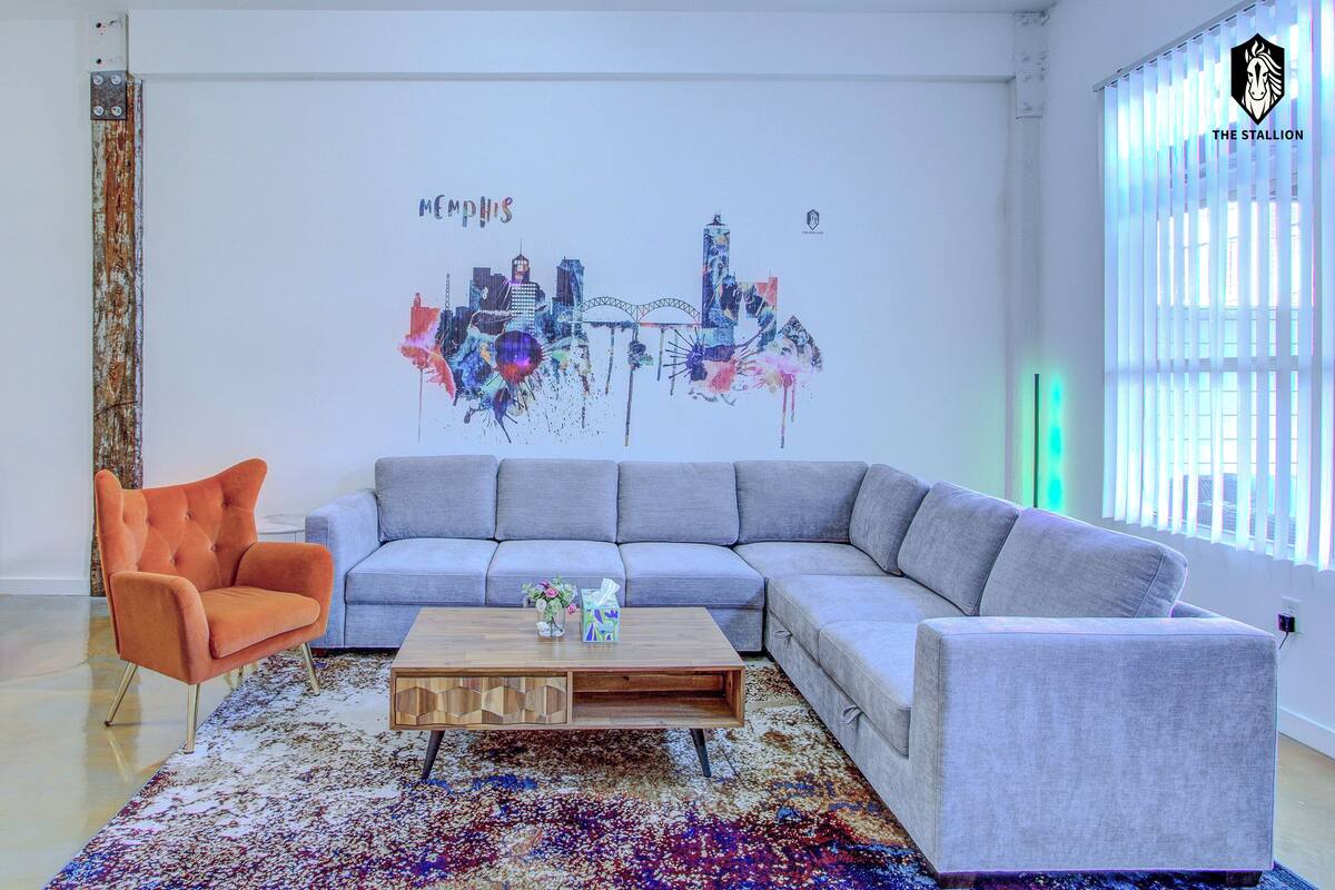 A modern living room with a sectional sofa, a wooden coffee table, and a vibrant abstract wall art piece.