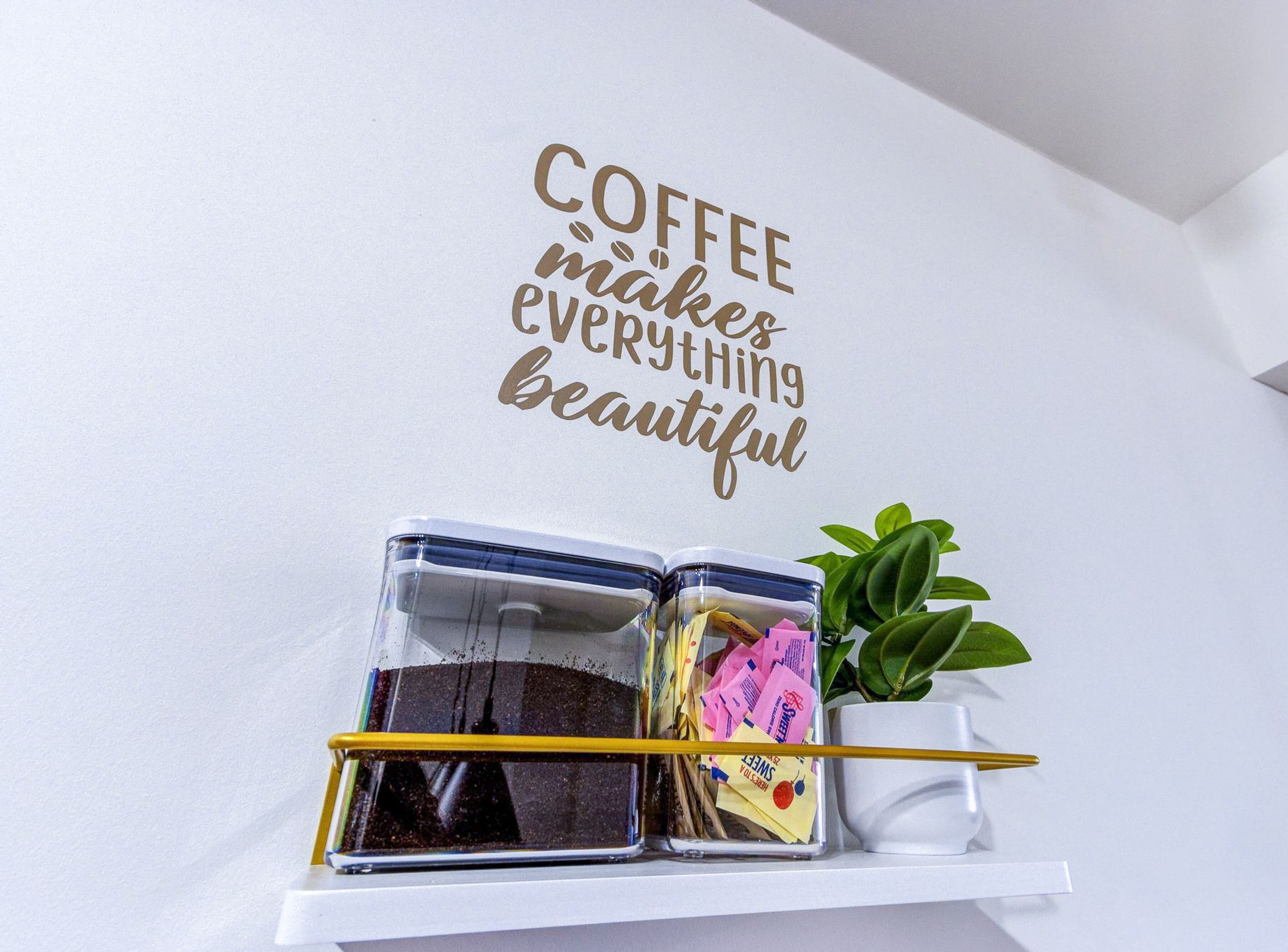 A wall with a motivational quote and a shelf with containers and a plant.