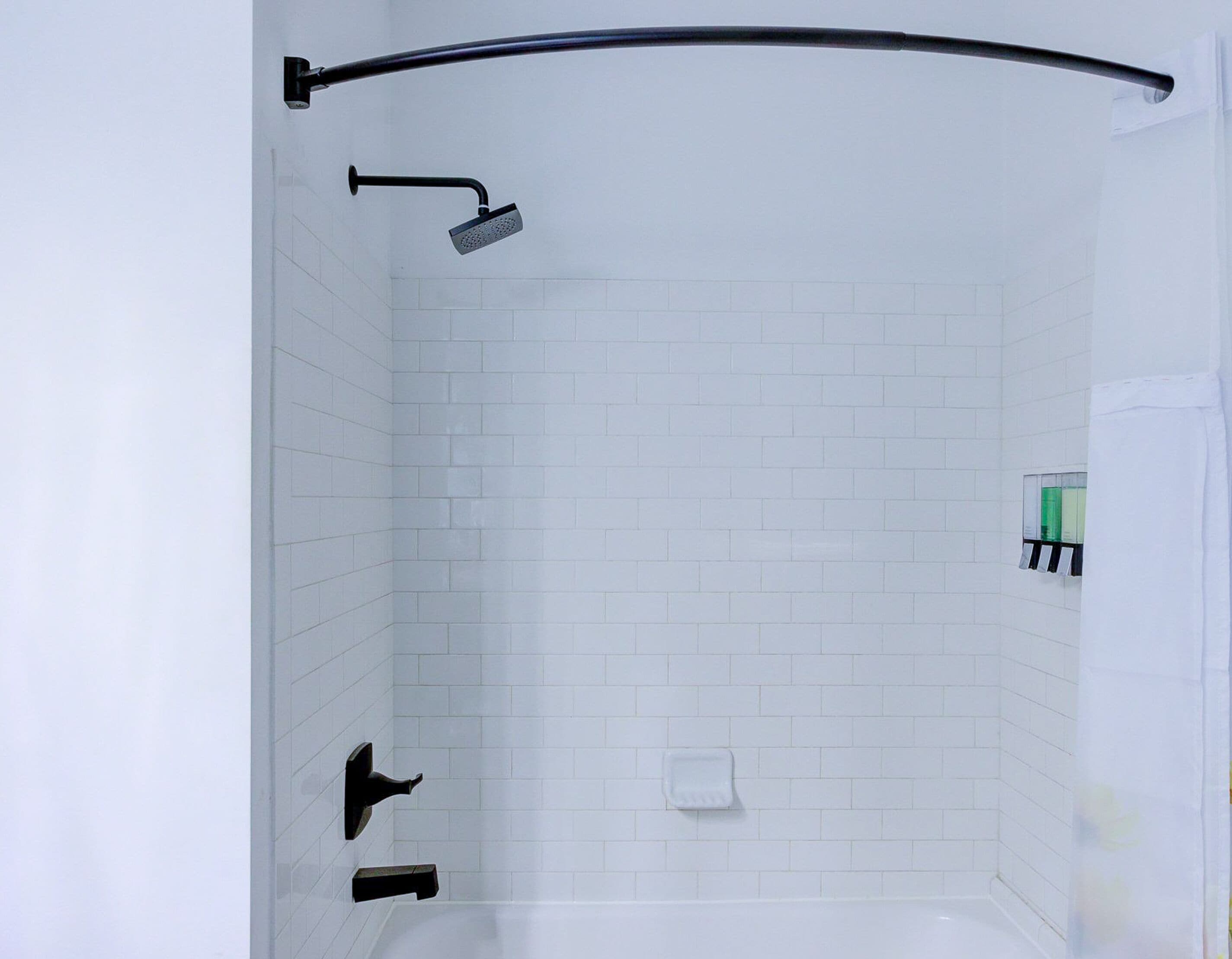 A modern bathroom with white subway tiles, a black showerhead, a handheld shower, and a soap dish.