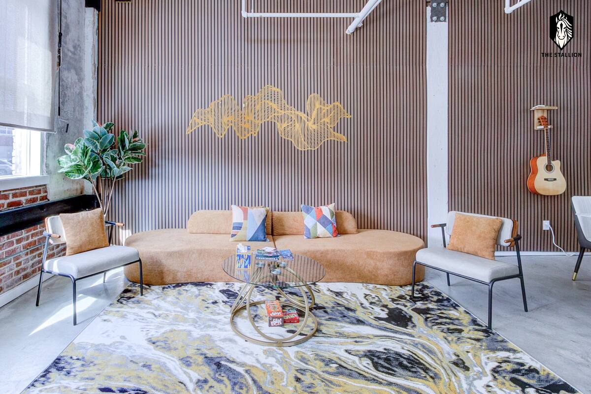 A modern living room with a sofa, two armchairs, a coffee table, and a decorative wall piece.