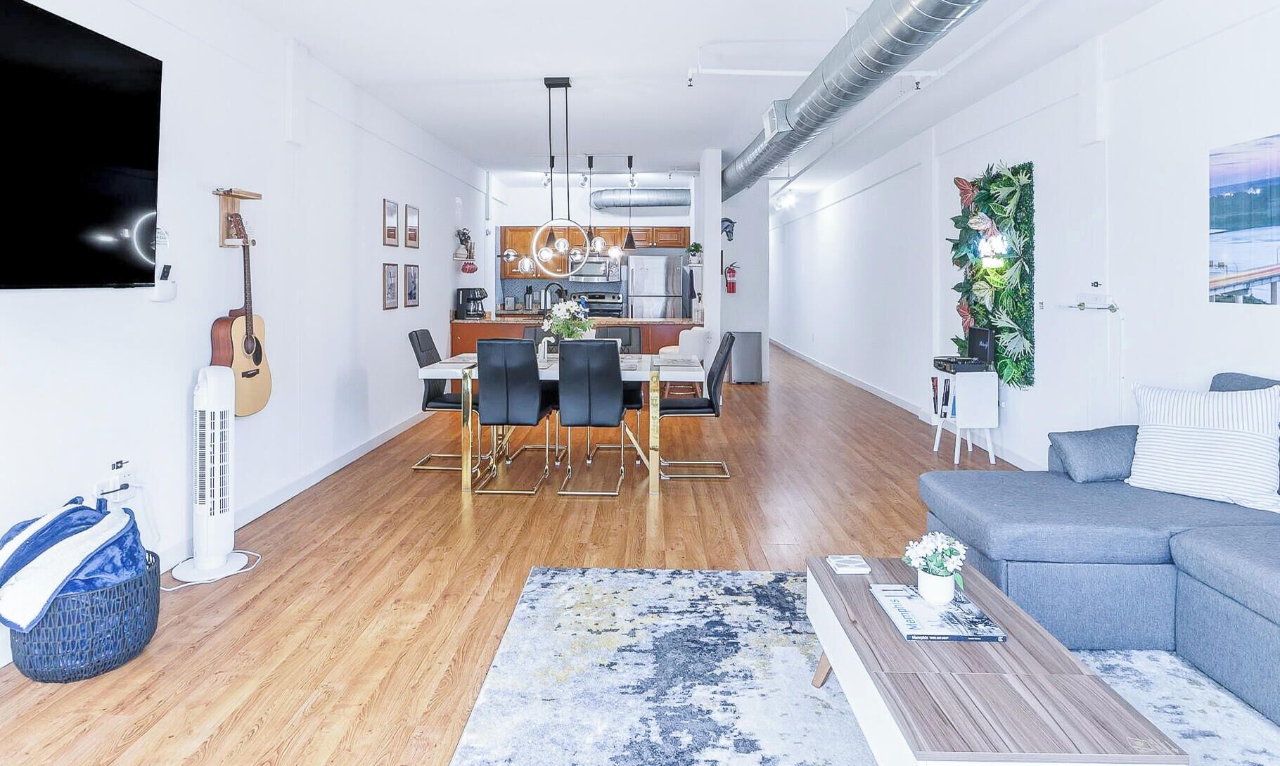A modern living space with a dining area, kitchen, and seating area.