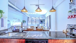 Una cucina moderna con un'isola centrale, illuminazione a sospensione e una macchina da caffè.