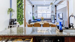 Una cucina moderna con lavastoviglie integrata, una zona pranzo con divano blu e un giardino verticale verde.