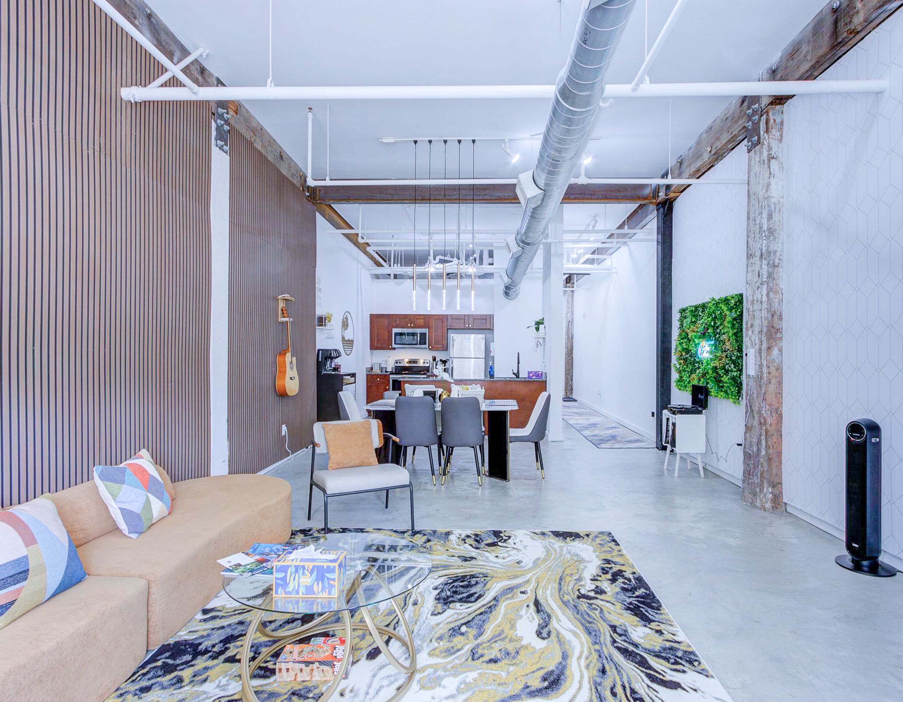 A modern interior with a sofa, a glass coffee table, and a dining area with chairs and a table.
