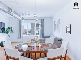 Una sala de estar moderna con comedor, ventanas amplias y vista a la ciudad.