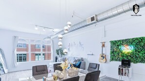 Spazio ufficio moderno con area ristoro, parete verde e insegna al neon, e una chitarra appesa al muro.