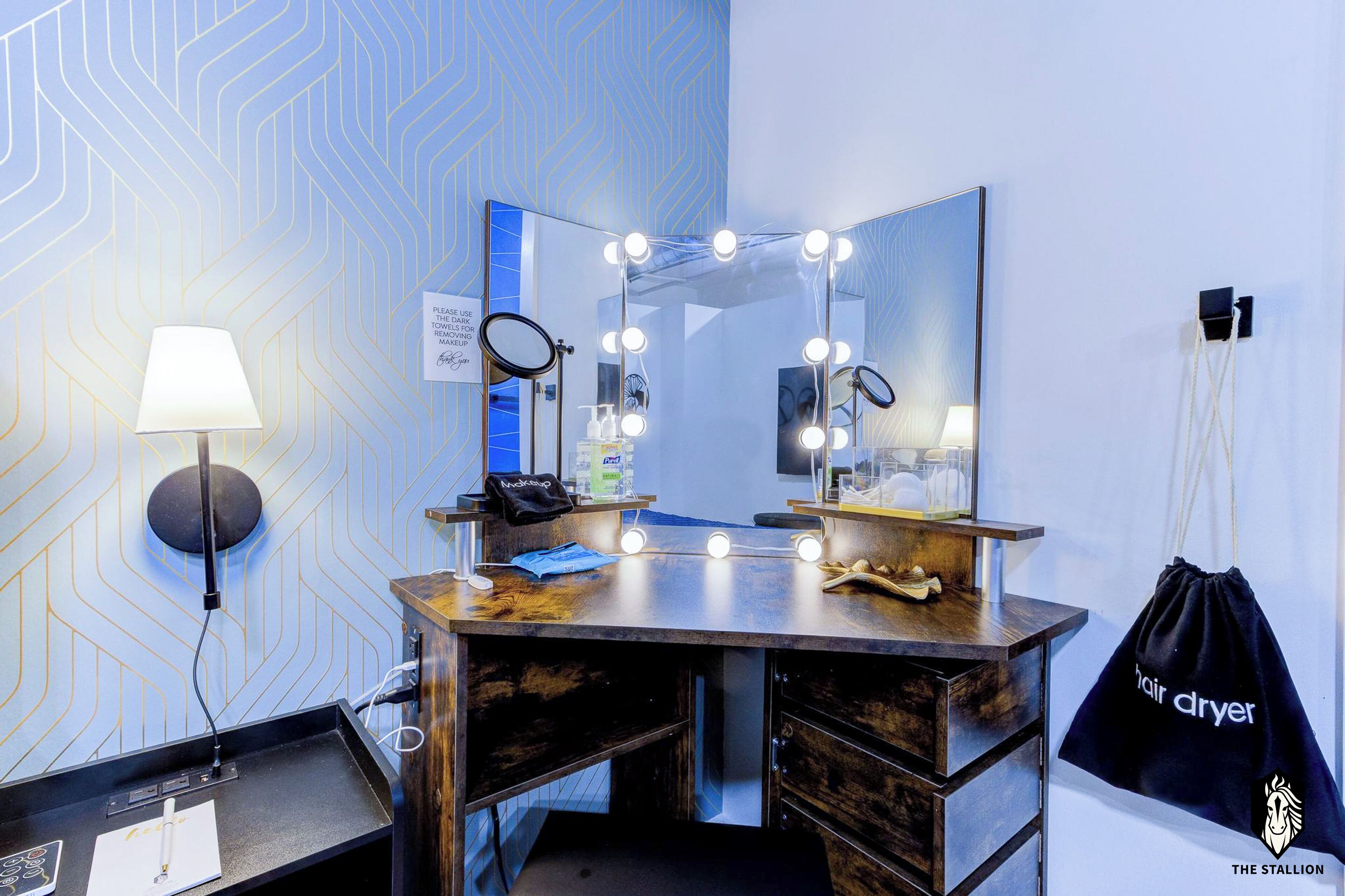 Habitación de hotel con espejo de tocador, luces, una bolsa negra y una pared con diseño geométrico.