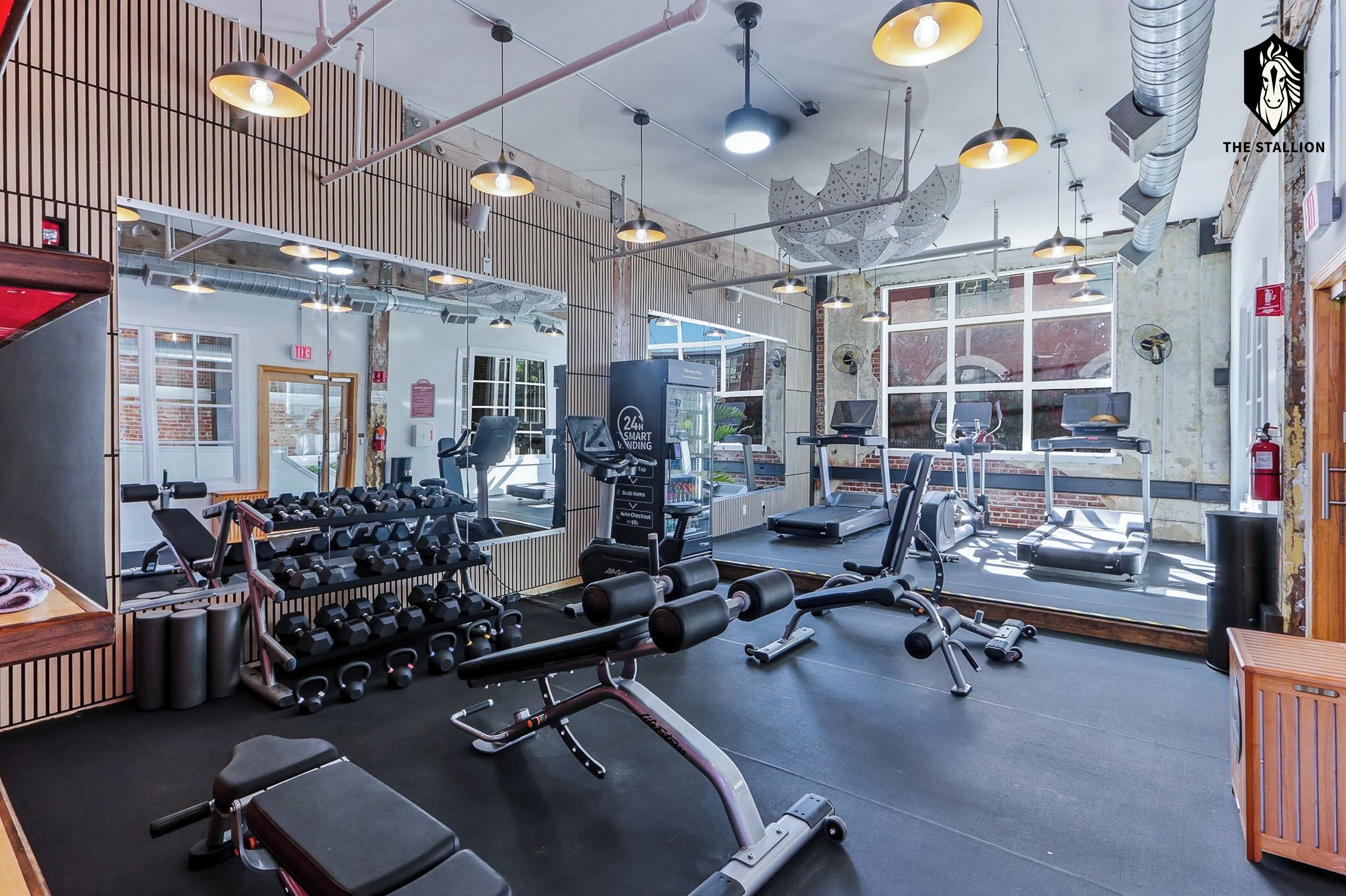 Ett gym med olika typer av träningsutrustning, inklusive hantlar, löpband och styrketräningsmaskiner.