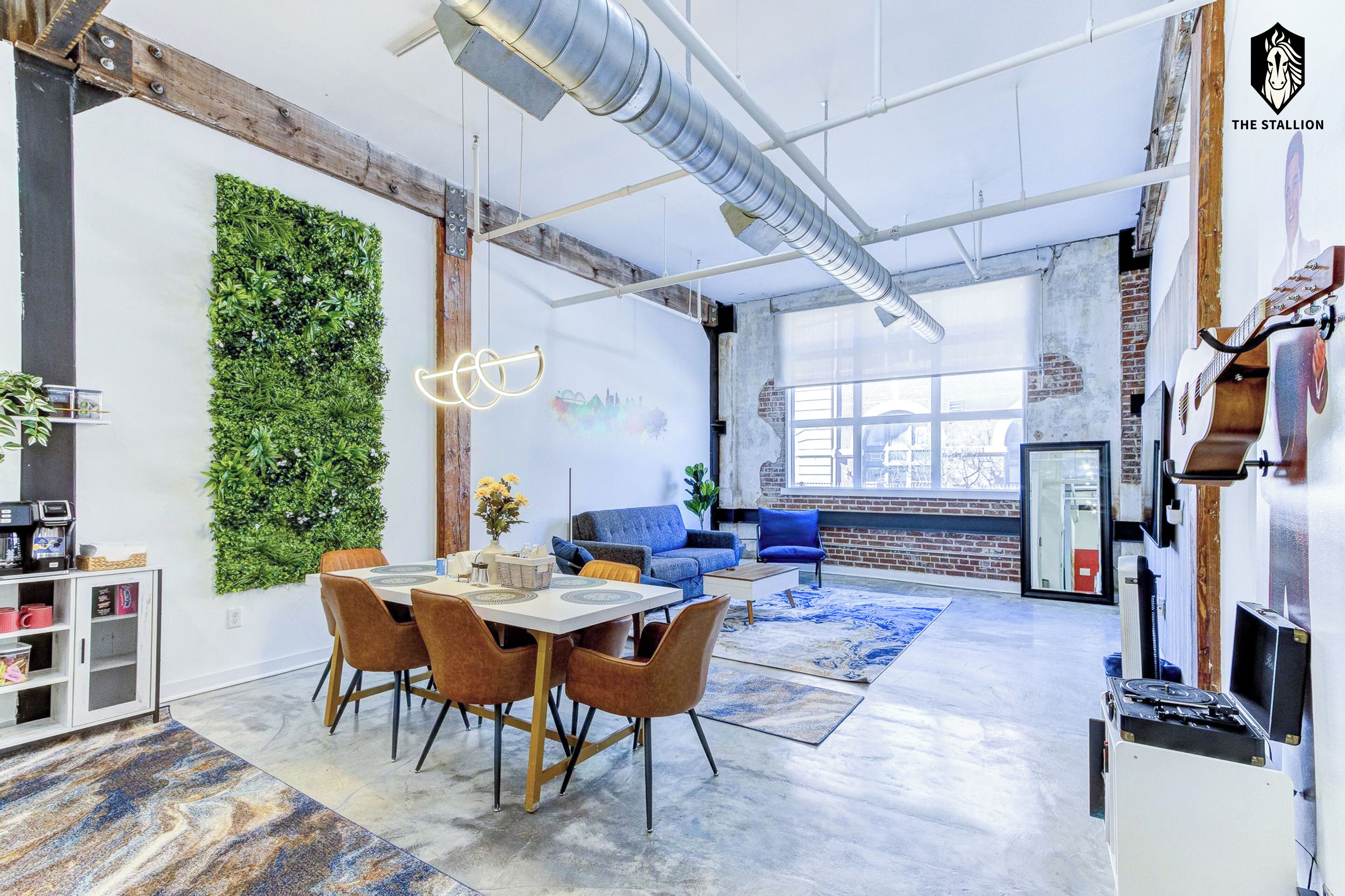 A modern interior with a dining area, a blue sofa, and a green wall.