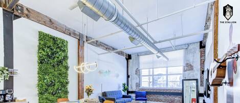 A modern interior with a dining area, a blue sofa, and a green wall.