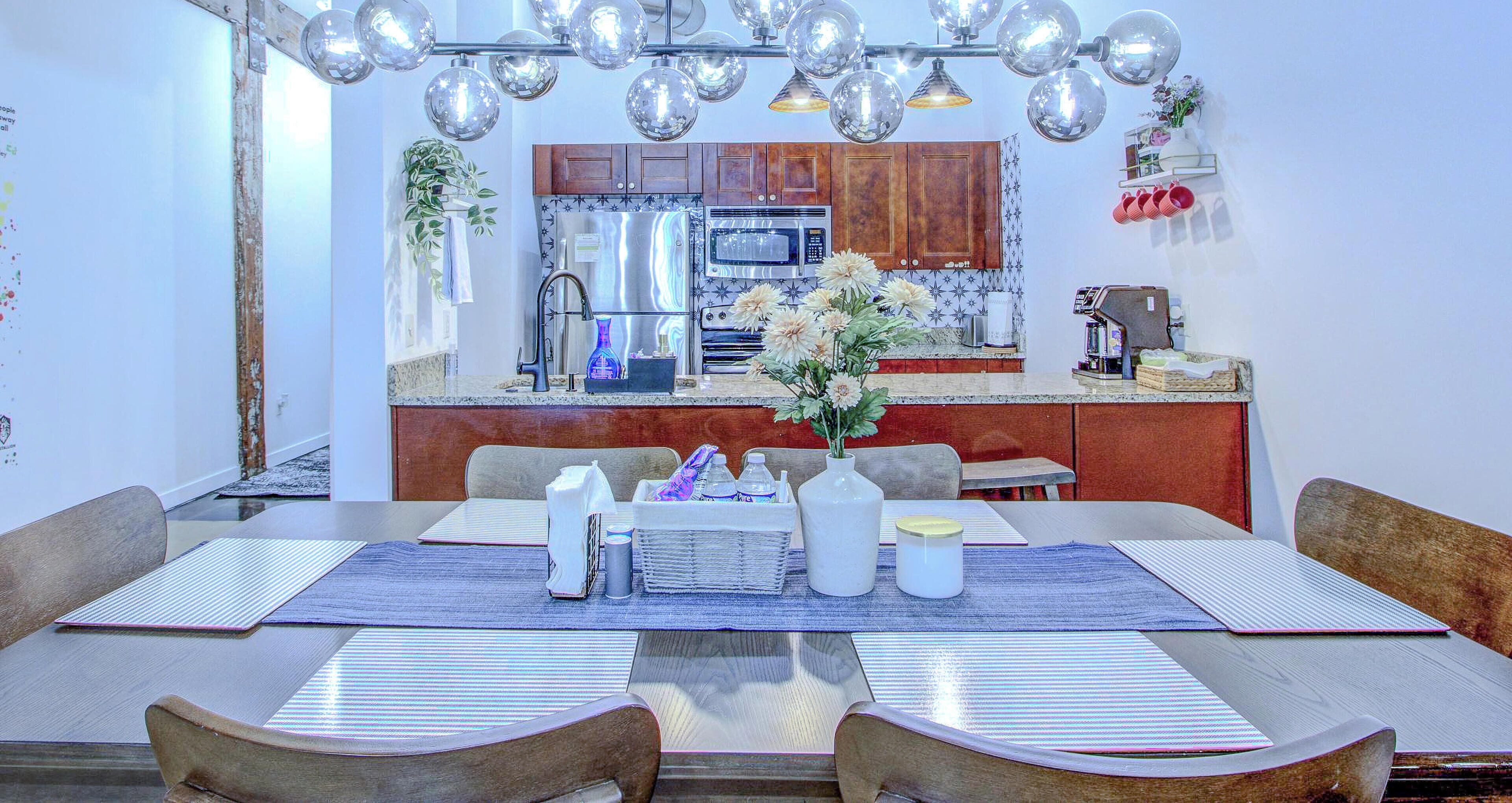 Un comedor moderno con una mesa central, sillas y una lámpara colgante.
