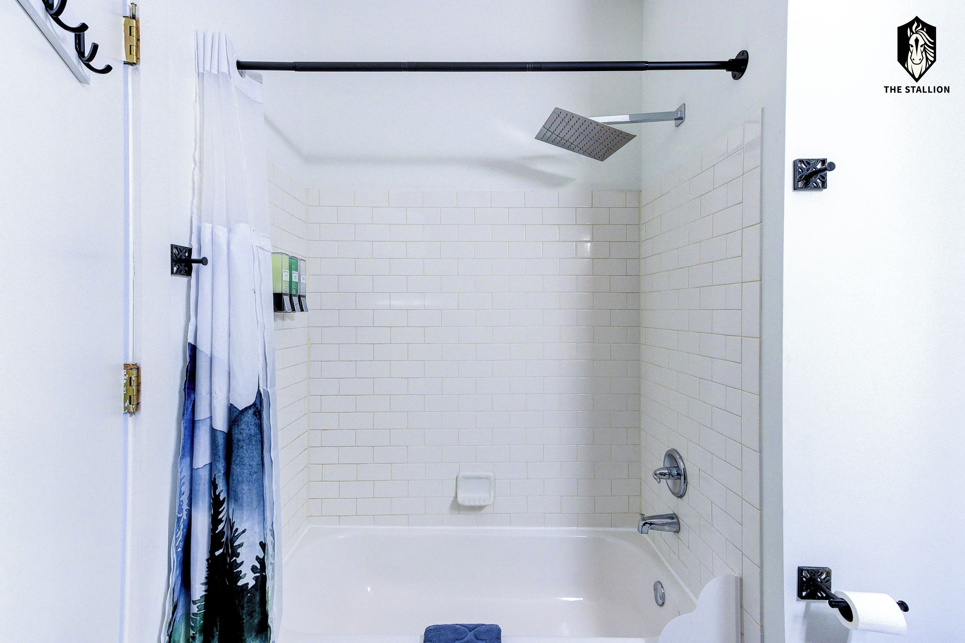 Un baño con bañera, ducha, toallero y soporte para papel higiénico.