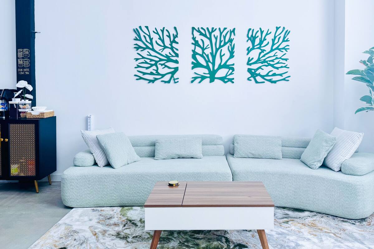 A living room with a light blue sofa, a wooden coffee table, and a wall with coral reef decals.