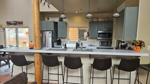 Una cocina moderna con una isla central, taburetes de bar y vistas al exterior.
