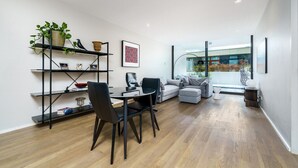 Een moderne woonkamer met een eethoek, een zithoek, een salontafel en een boekenkast.