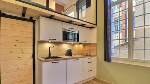 A compact kitchen with white cabinets, a built-in oven, and a window with a view of the outside.