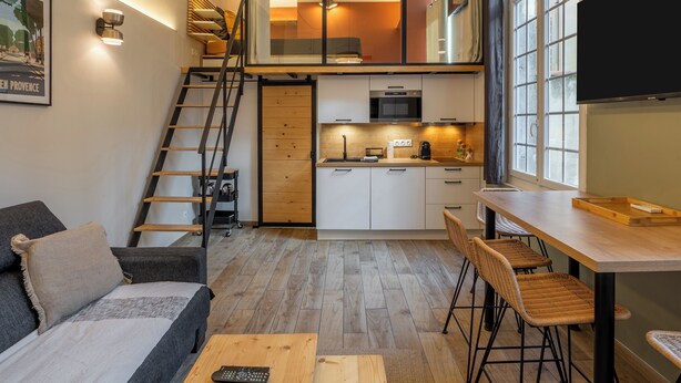 A compact living space with a loft bedroom, kitchenette, and a dining area.