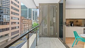 A modern apartment with a balcony, a kitchen with a dining area, and a view of the cityscape.