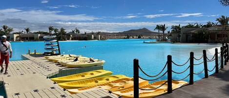 A poolside area with kayaks lined up and a person walking.