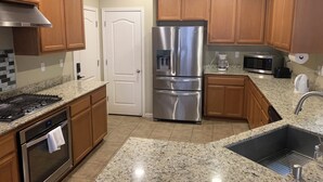 A modern kitchen with granite countertops, stainless steel appliances, wooden cabinets, and a built-in oven.