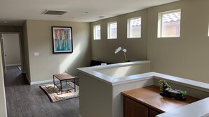 A modern kitchen with a wooden countertop, a sink, and a window above it. There is a small stool and a rug on the floor.